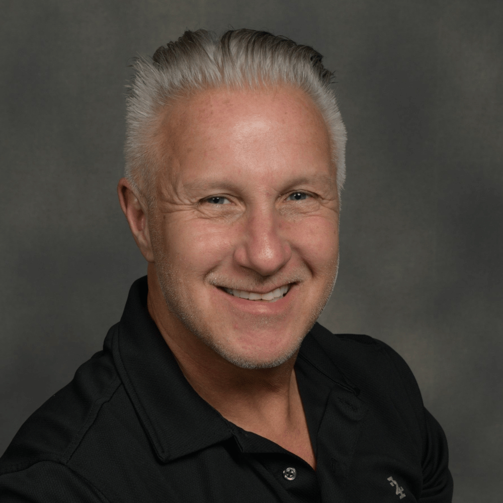 Headshot of Dr. Brice Gerlach smiling against a gray background.