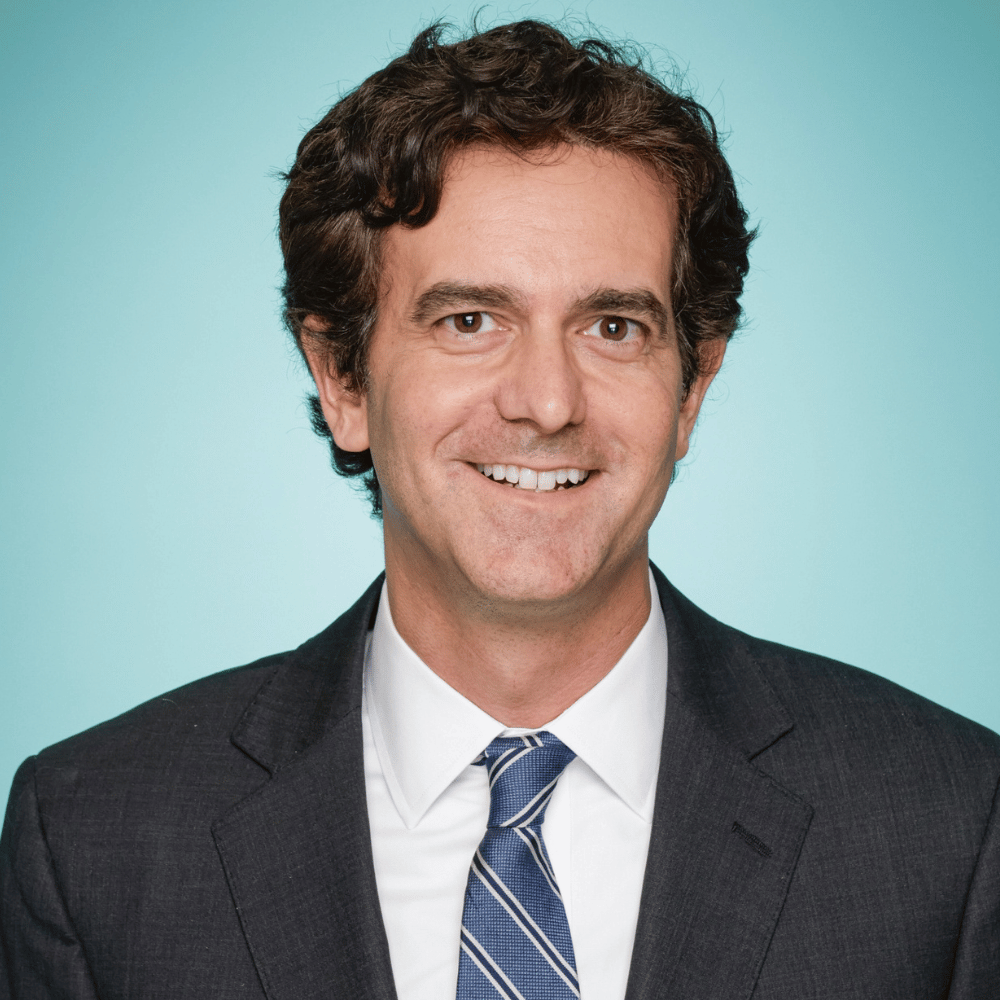 Headshot of Rev. Dr. Scott Kenefake wearing glasses and a dark suit against a gray background.