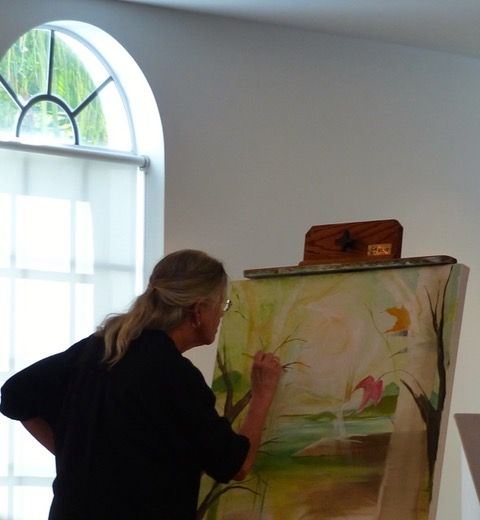 Susan Pratt working on a vibrant, creative painting project in an art space.