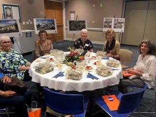 A group of women gathered closely around a beautifully decorated dining table sharing a meal and fellowship.