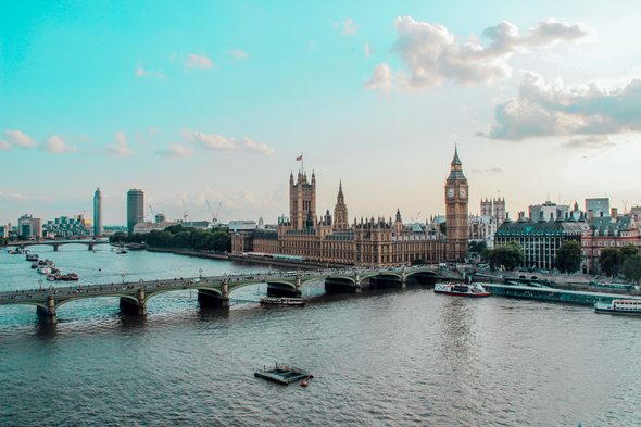 London’s Houses of Parliament and Big Ben beside the Thames, with Westminster Bridge under a bright sky