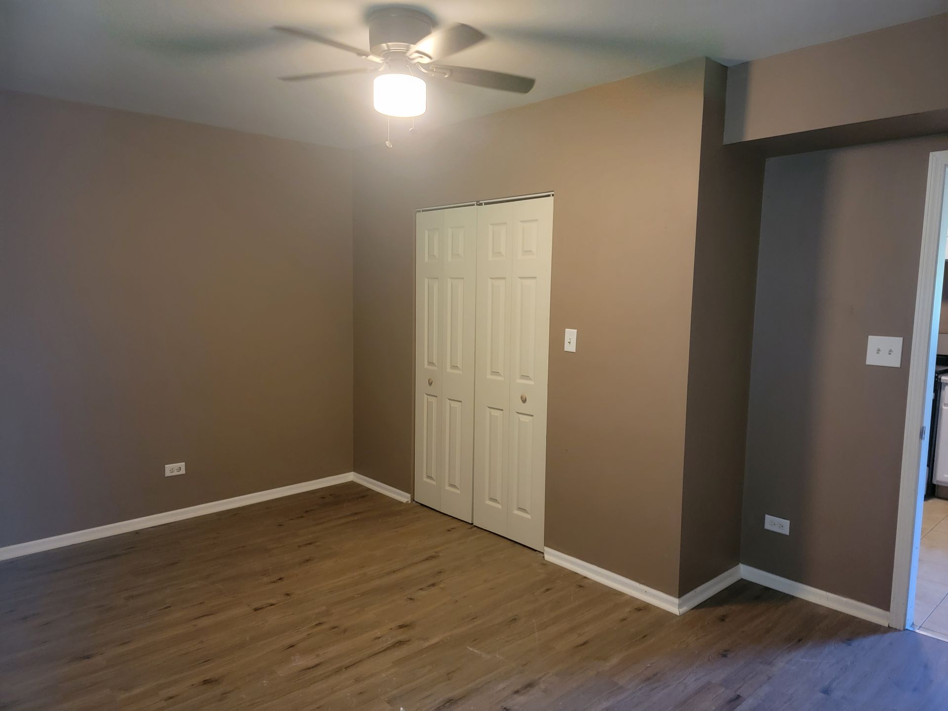 An empty room with a ceiling fan and a closet