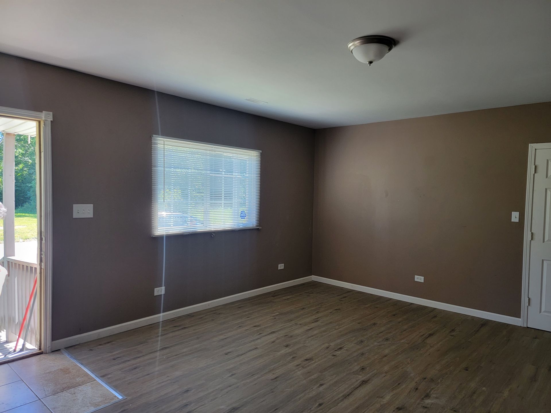 An empty living room with hardwood floors and a window.