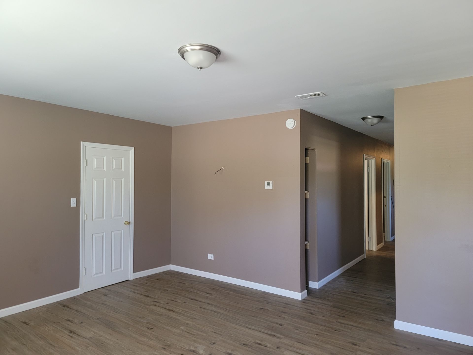 An empty room with a door and a light on the ceiling.