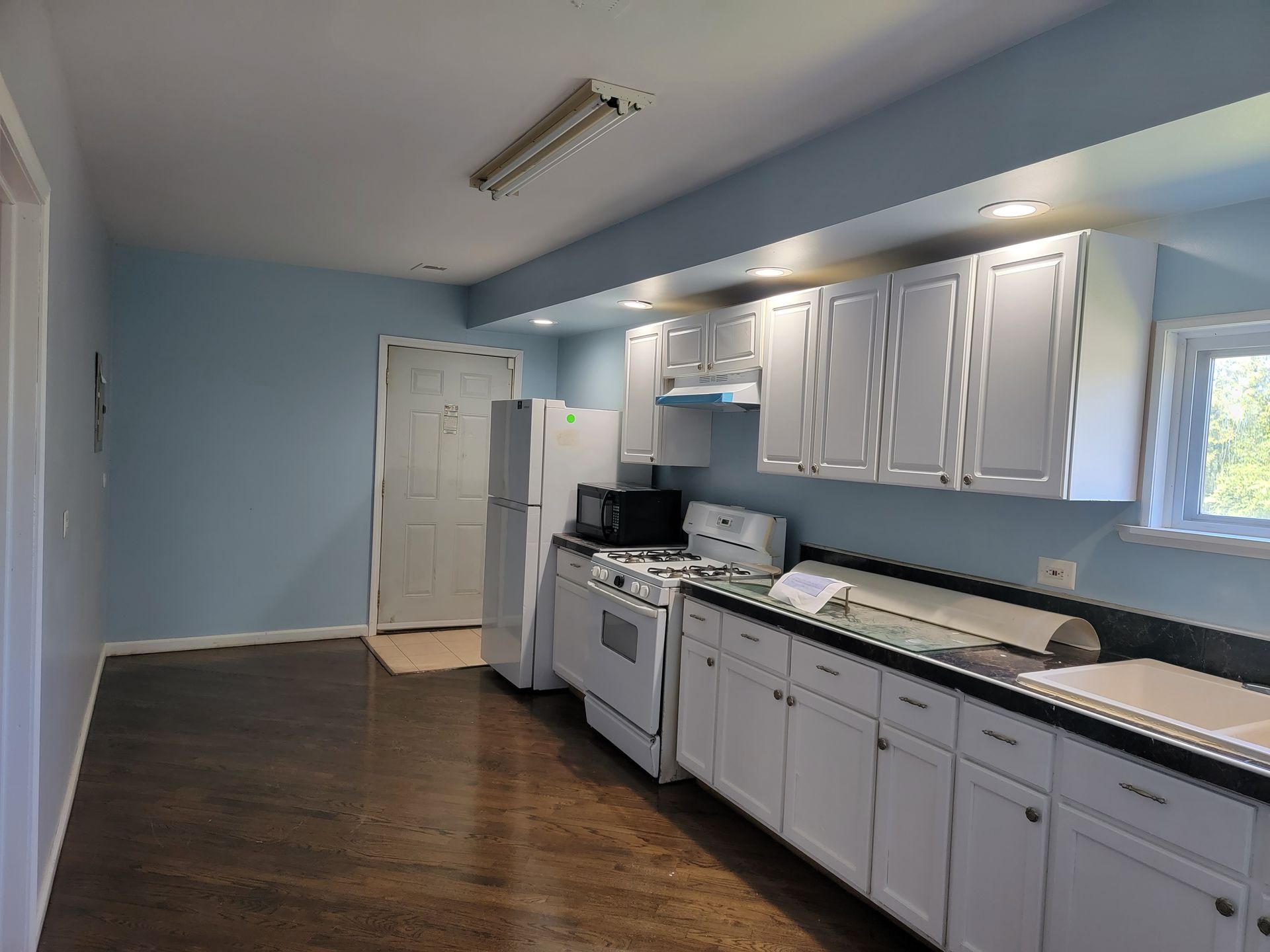 An empty kitchen with blue walls and white cabinets