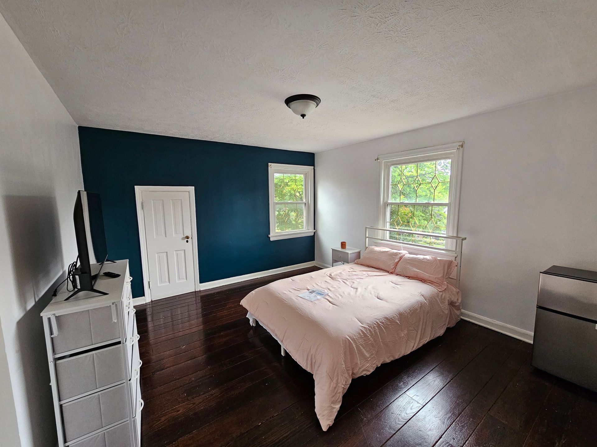 A bedroom with a bed , dresser , and television.