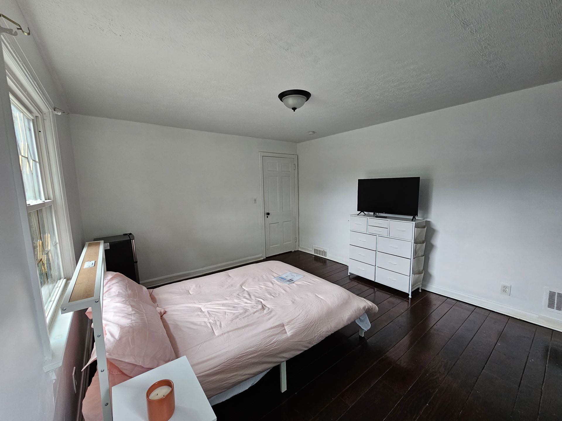 A bedroom with a bed , dresser , and television.