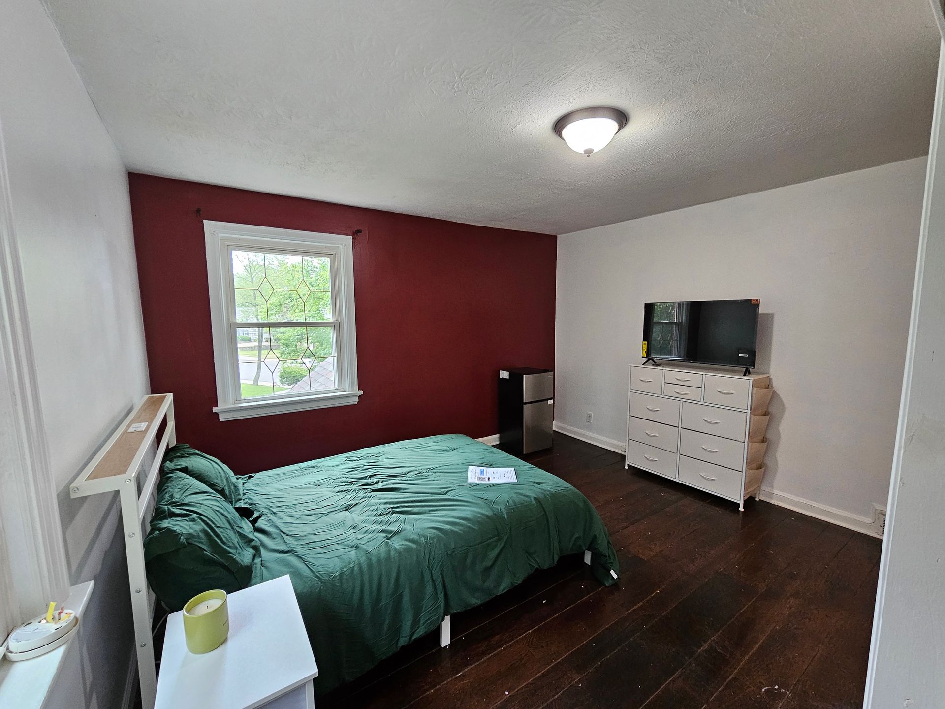 A bedroom with a bed , dresser , and television.