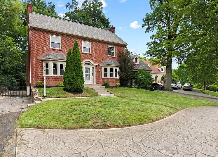 A large brick house with a large lawn in front of it.