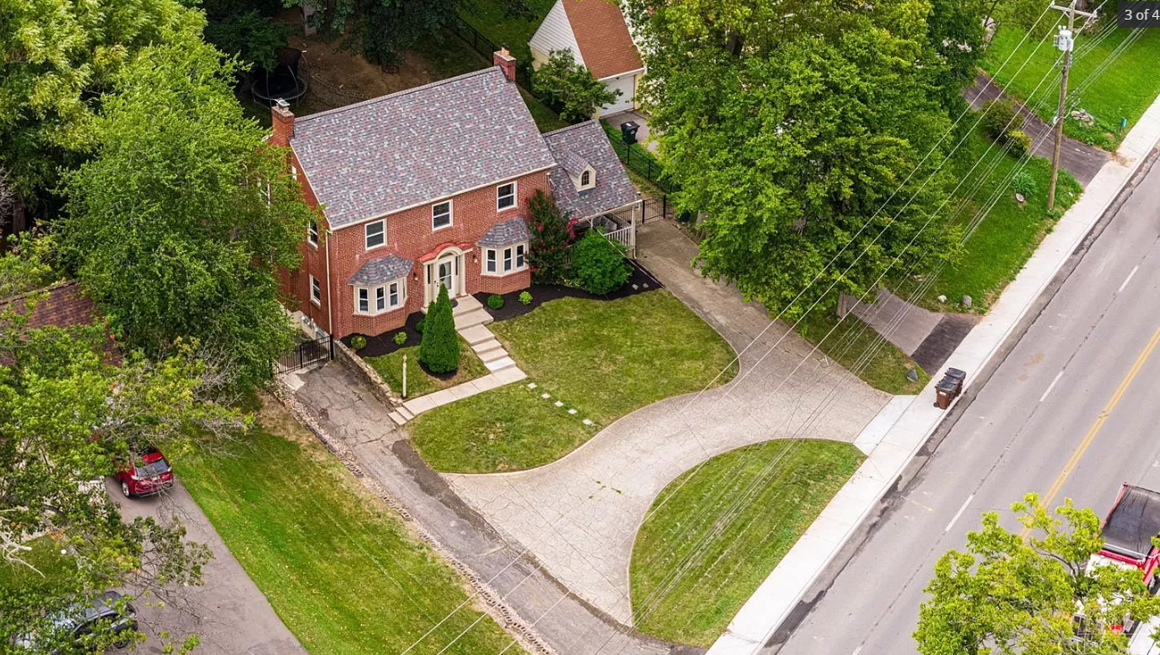 An aerial view of a brick house with a driveway and a car parked in front of it.
