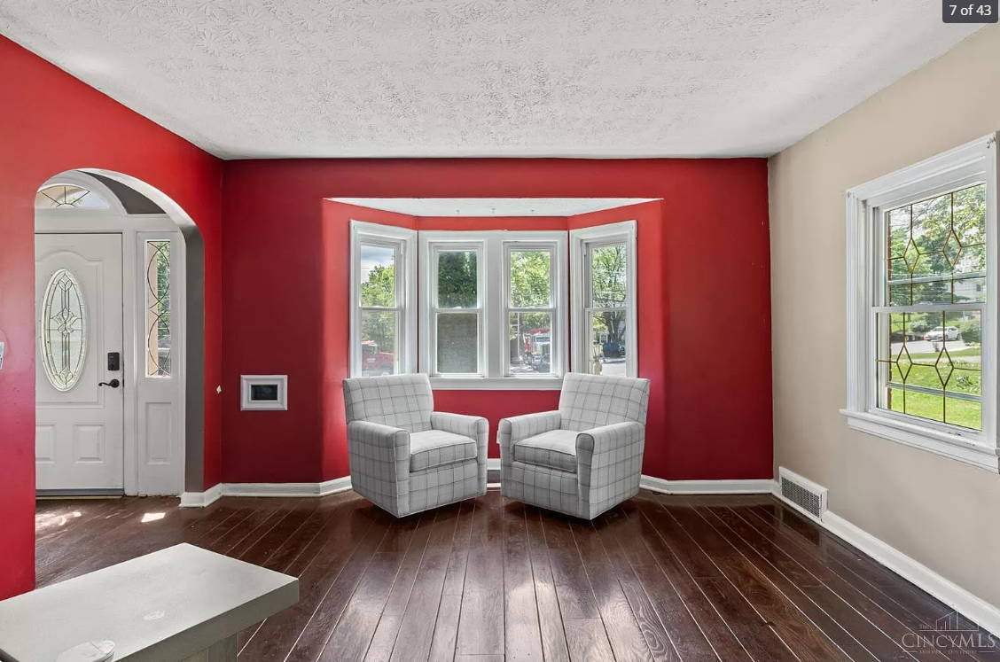 A living room with red walls and white chairs