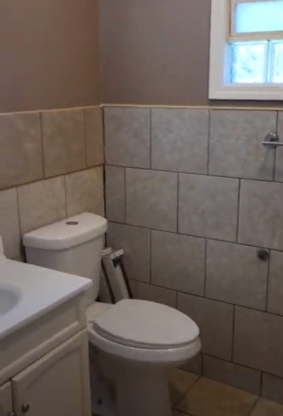 A bathroom with a toilet , sink and window