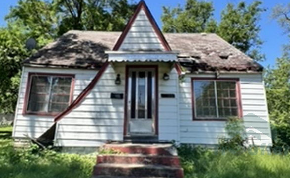 A small white house with a red trim and stairs in front of it.