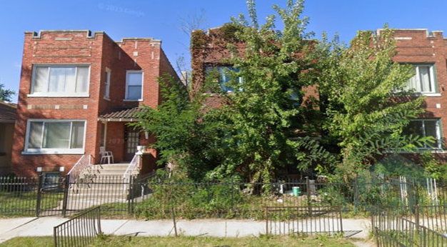 A row of brick buildings with trees in front of them.