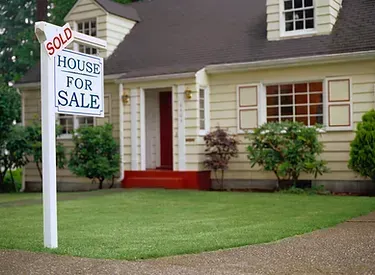 A house with a sold house for sale sign in front of it.