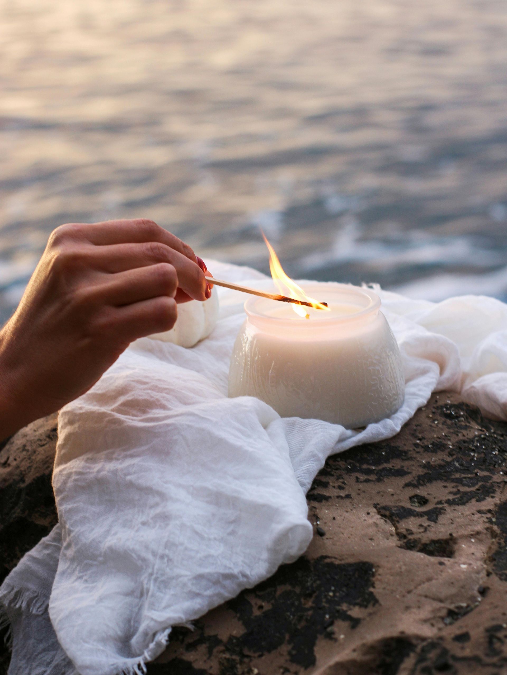 Hand Lighting a White Candle on Rocks — Vivienne Celebrant - Gold Coast Wedding Celebrant in Mudgeeraba, QLD