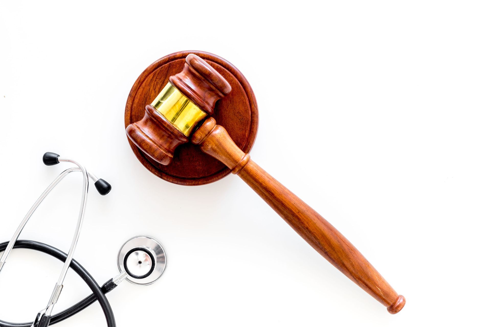 A wooden judge's gavel resting on its sounding block next to a medical stethoscope on a white background.