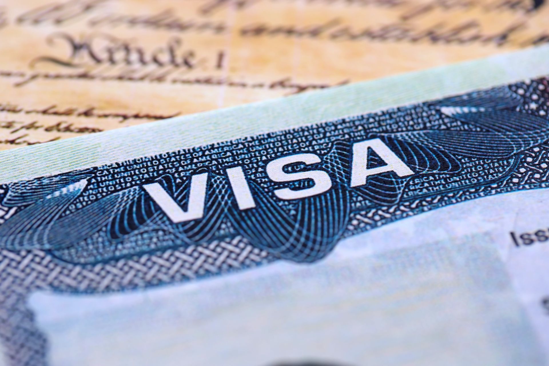 Close-up of a visa document with bold white “VISA” text on a blue security background