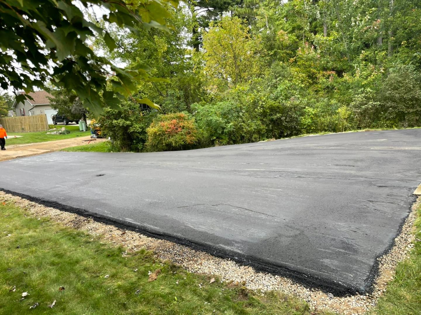 Freshly paved asphalt path curving through a green park with trees and shrubs