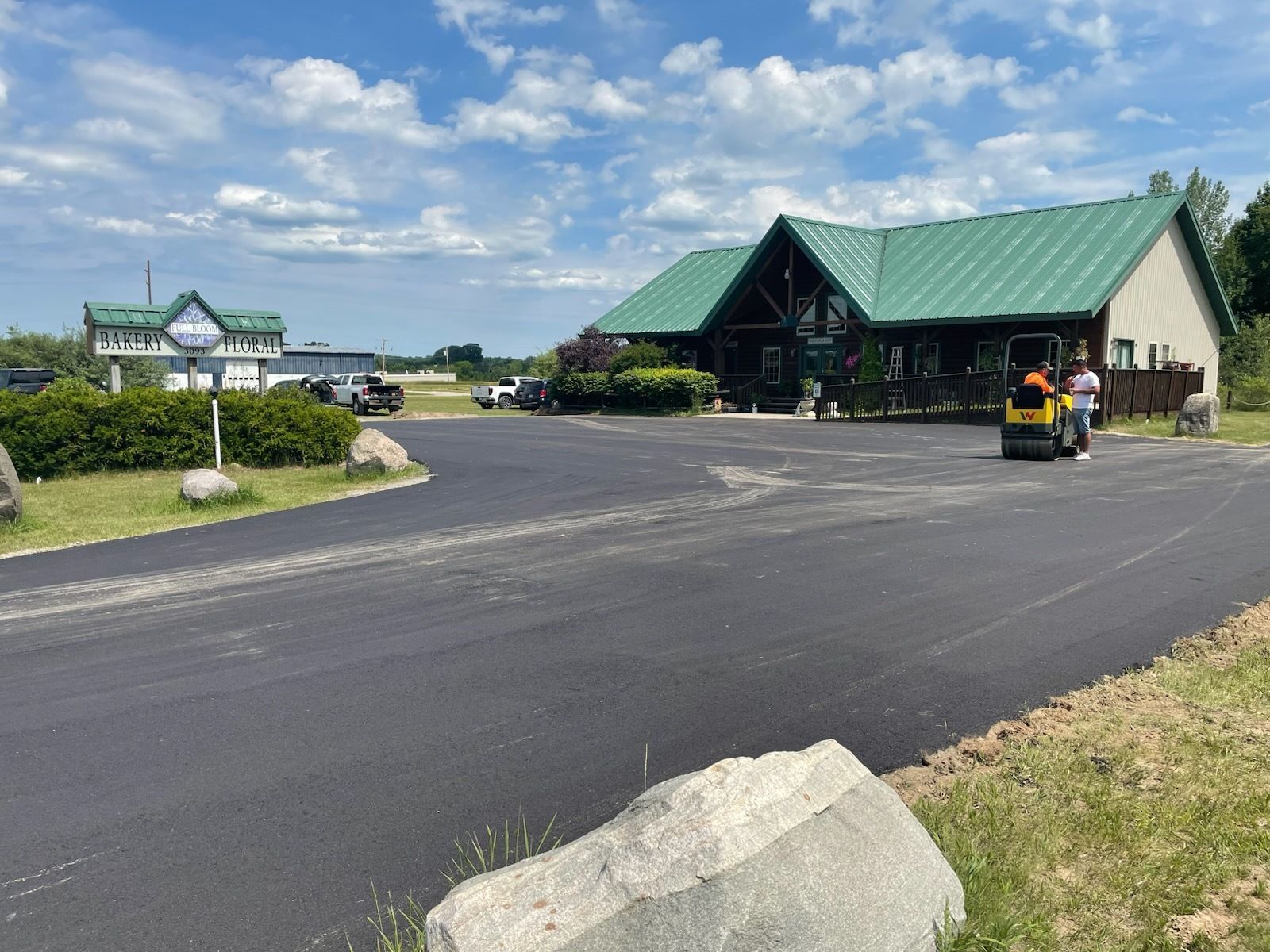 Green-roofed building and parking lot under a partly cloudy sky, with a golf cart in front