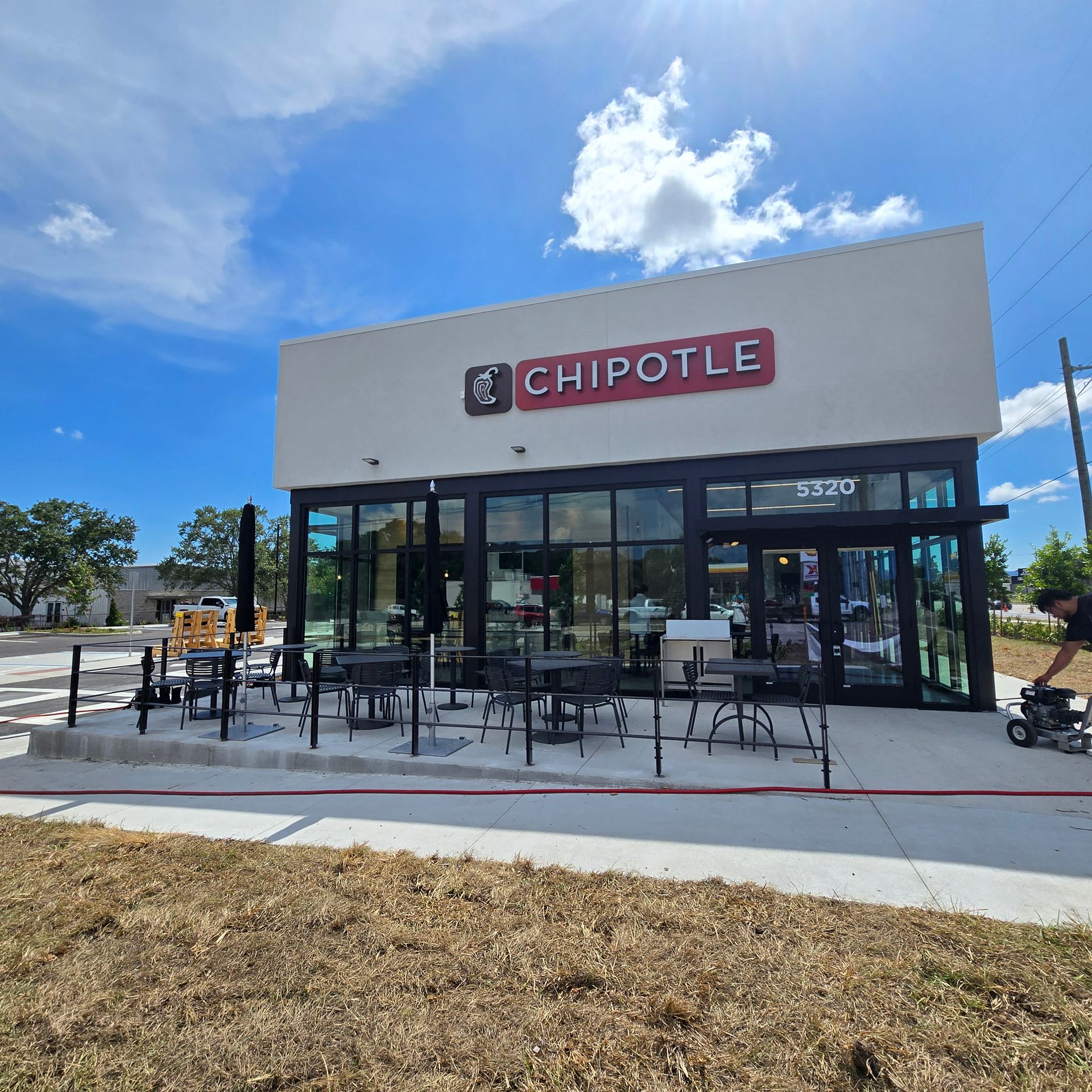 Chipotle restaurant exterior with patio seating under a bright blue sky
