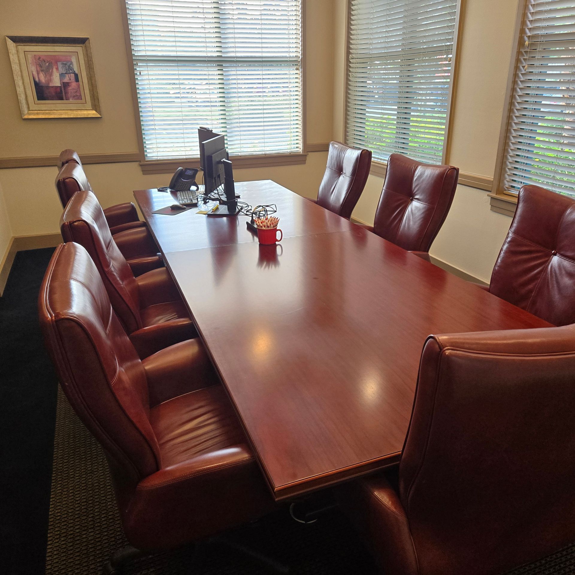 Reception desk in office. Light wood floors and countertops. Desks with computers and chairs.