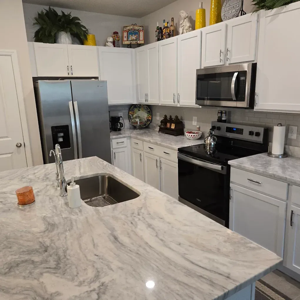Modern white kitchen with marble island, stainless steel appliances, and white cabinets
