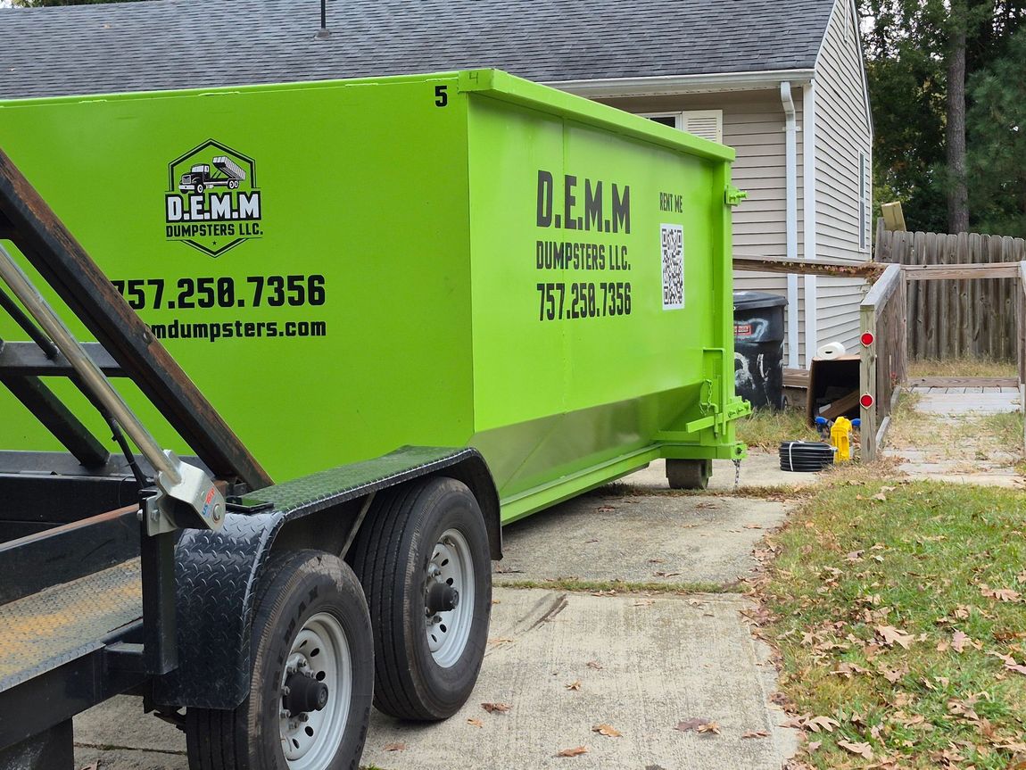 Bright green industrial dumpster outdoors with some items in the background.