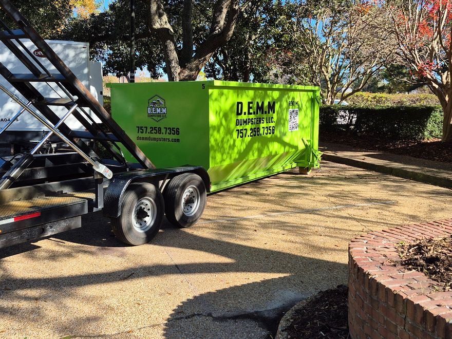 Bright green industrial dumpsters filled with debris are under a dark gray awning.