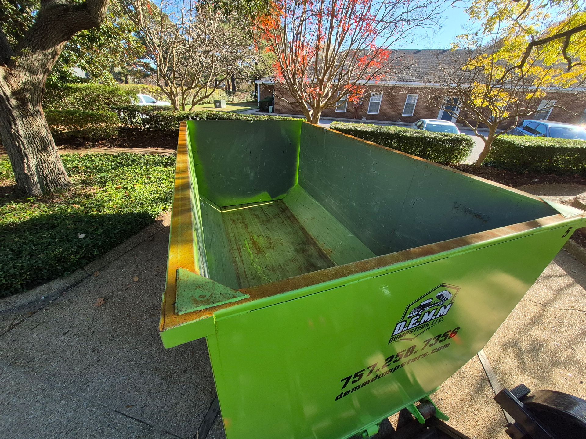 Two stacked, bright green dumpsters against a partly cloudy blue sky.