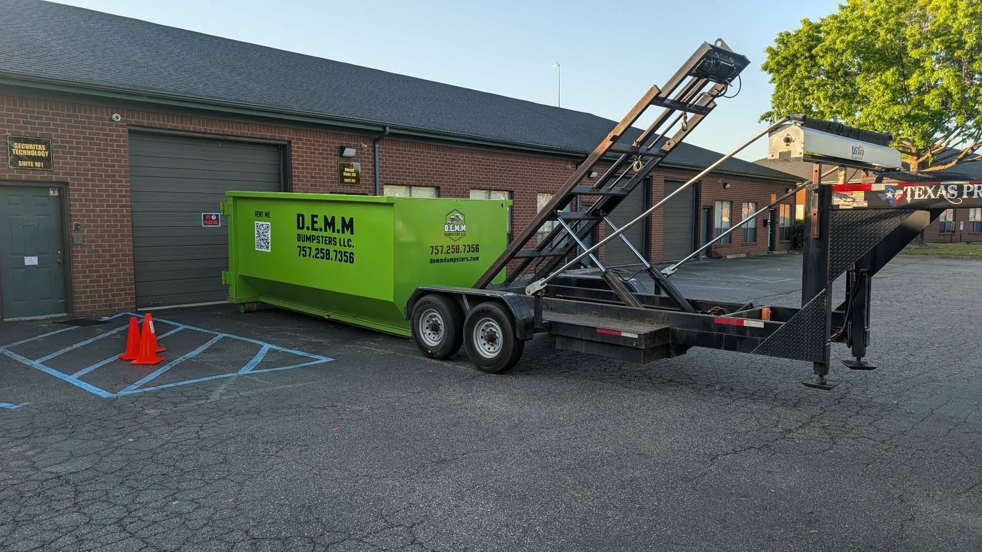 Two stacked, bright green industrial dumpsters under a blue sky.