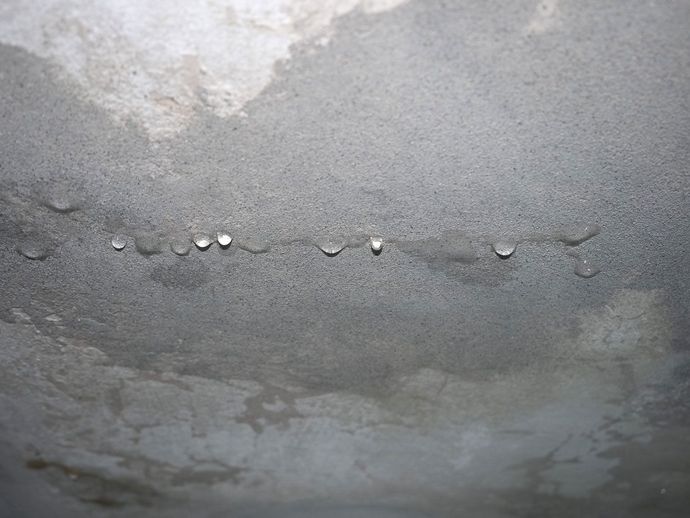Close-up of a gray concrete surface with a horizontal crack and water stains Close-up of a gray concrete surface with a horizontal crack and water stains