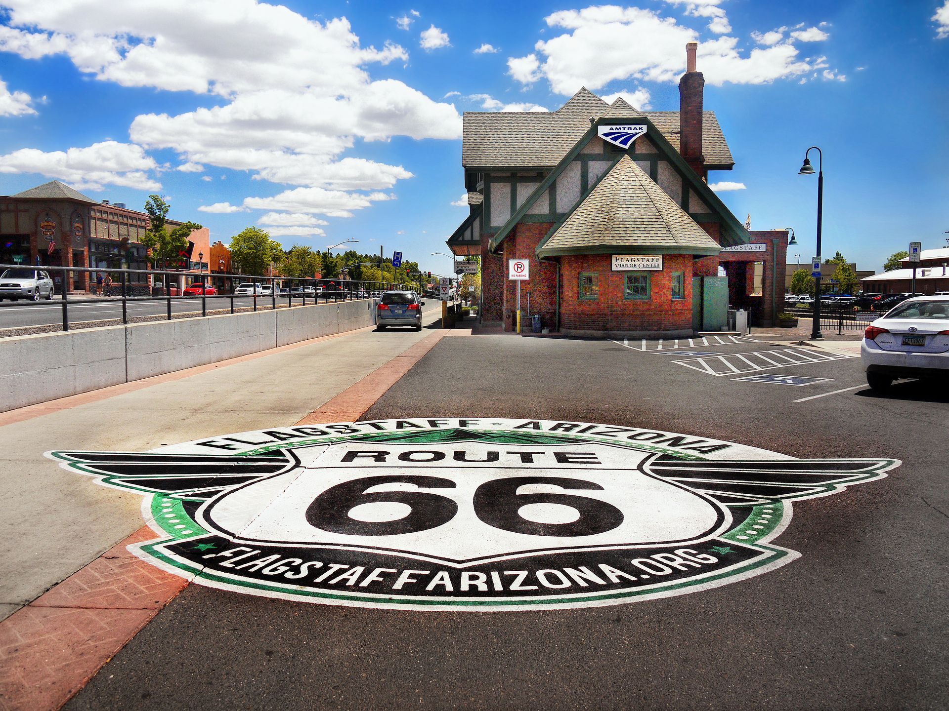 Route 66 road mural in front of a small building under a blue sky with clouds