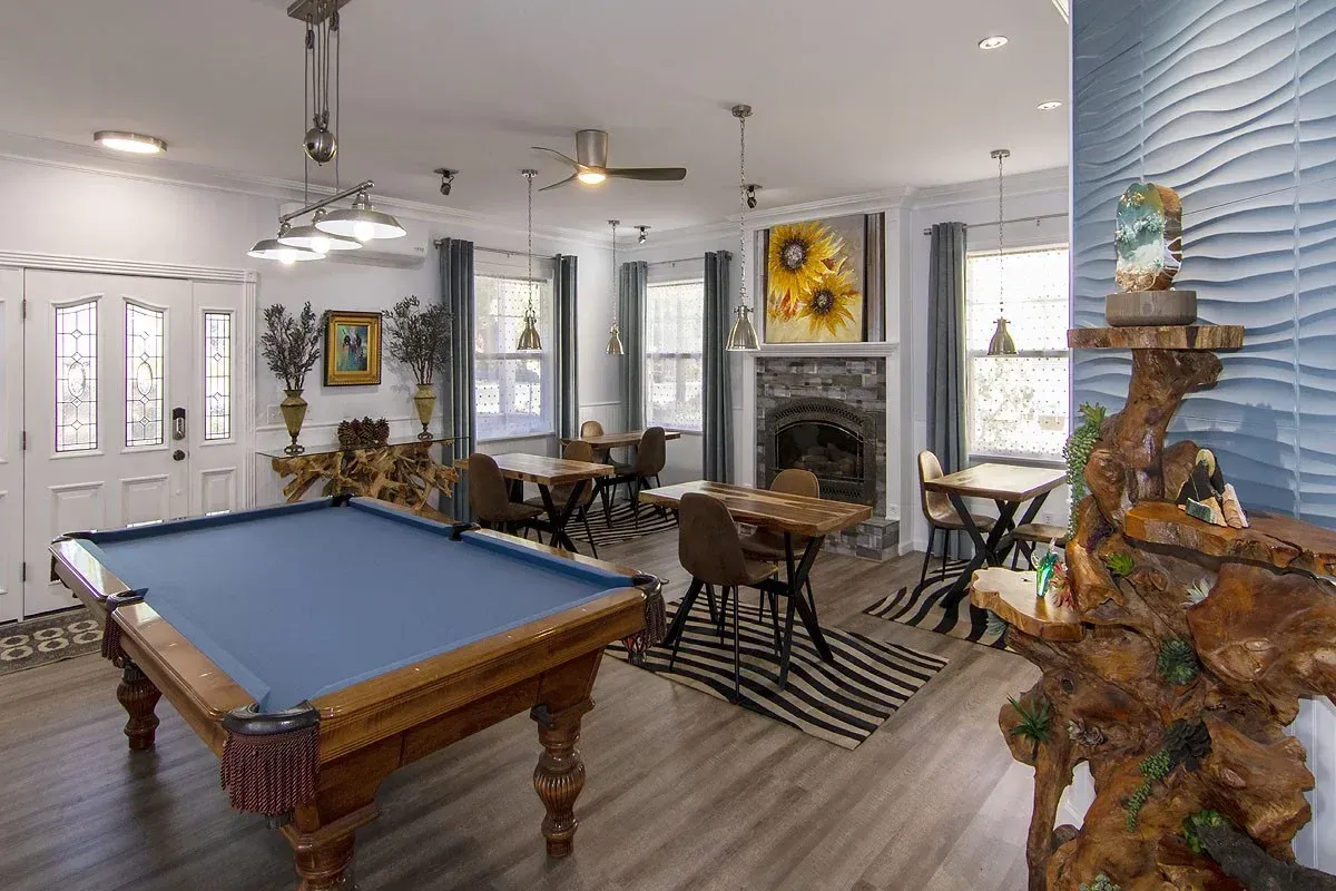 Spacious living room with pool table, fireplace, seating area, and large window by the water.