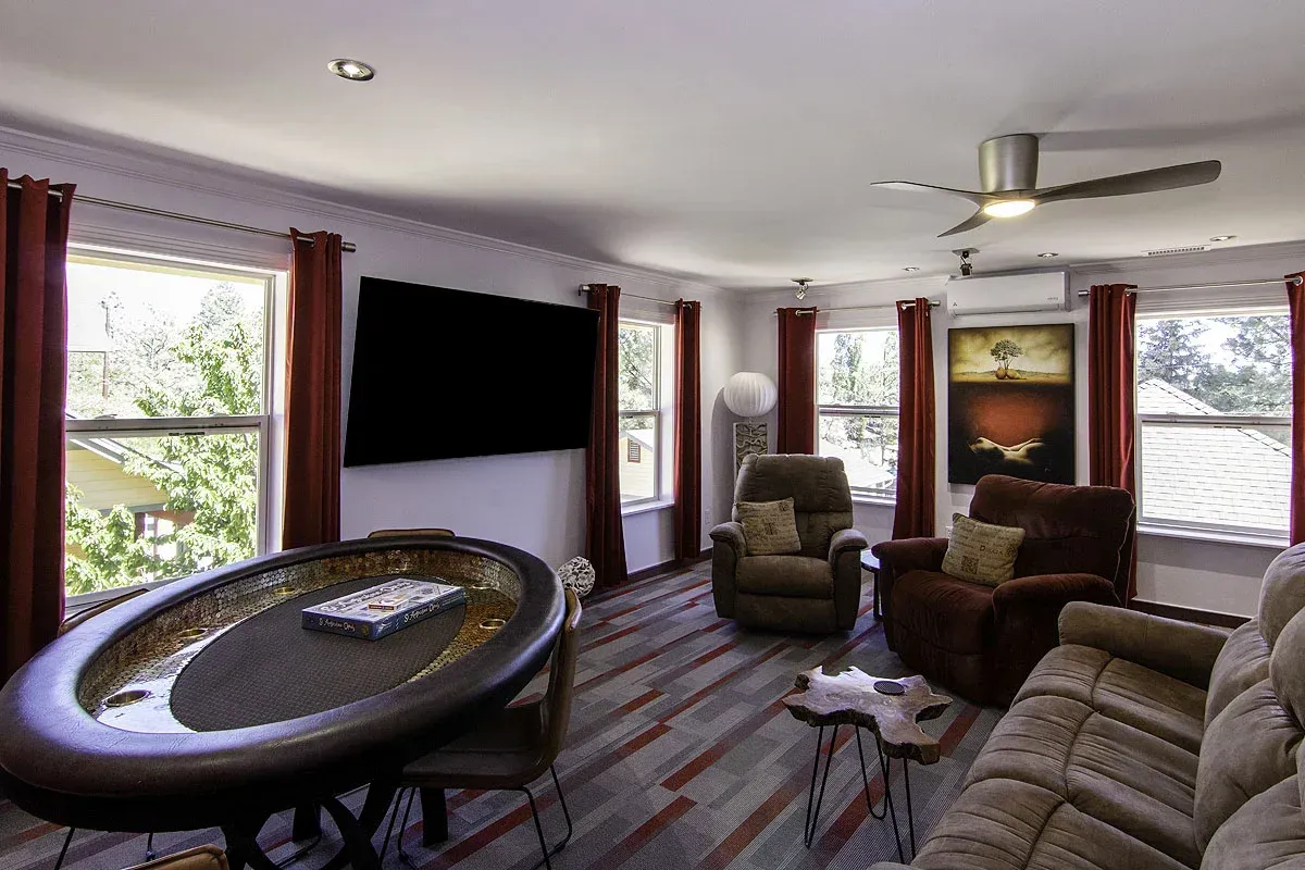 Cozy living room with recliners, TV, striped rug, and large windows with daylight