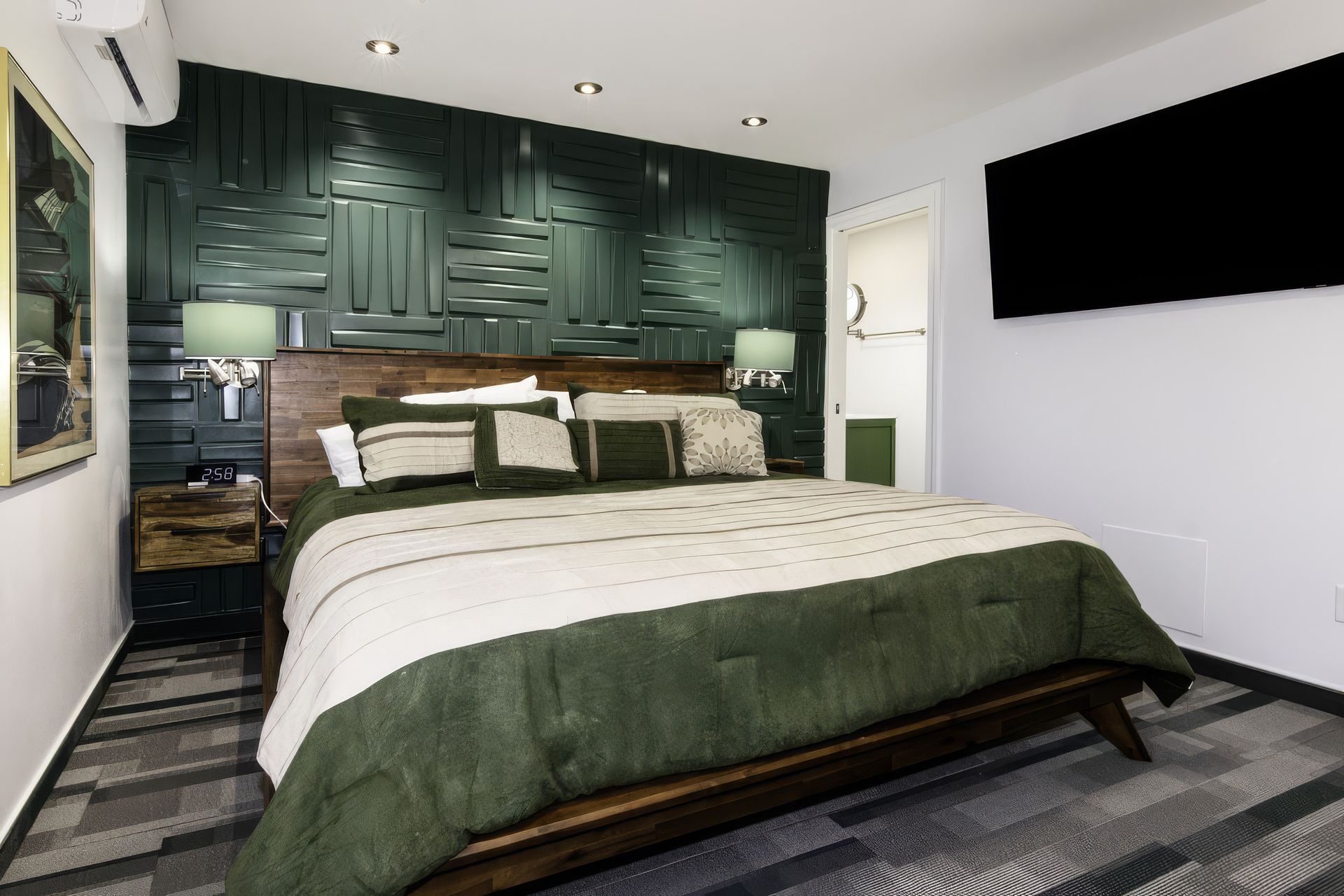 Modern bedroom with green accent wall, king bed, bedside lamps, and striped gray rug