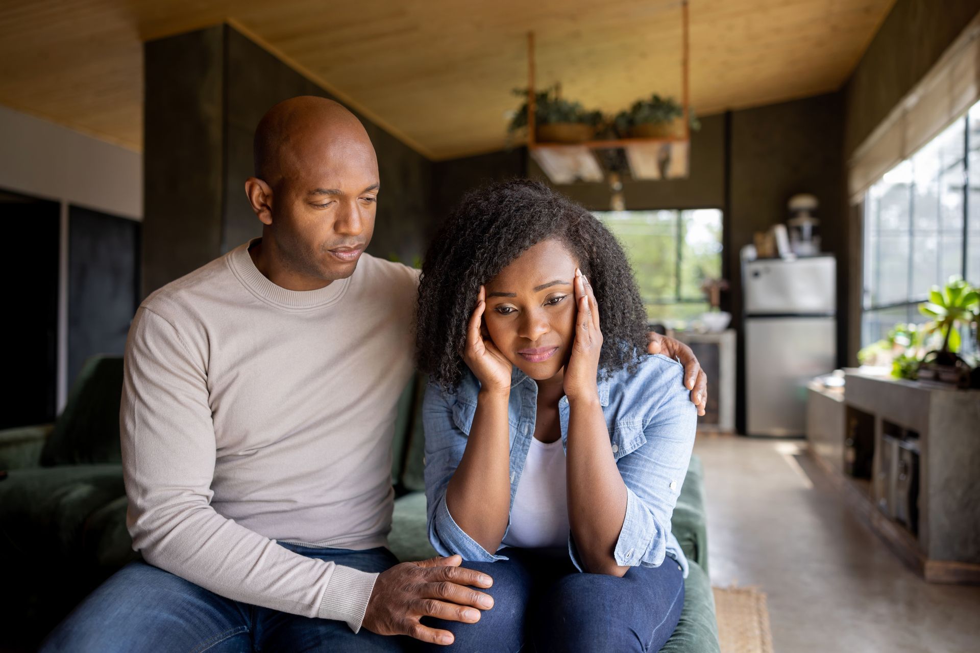 Man comforts woman, both appear distressed, indoors.