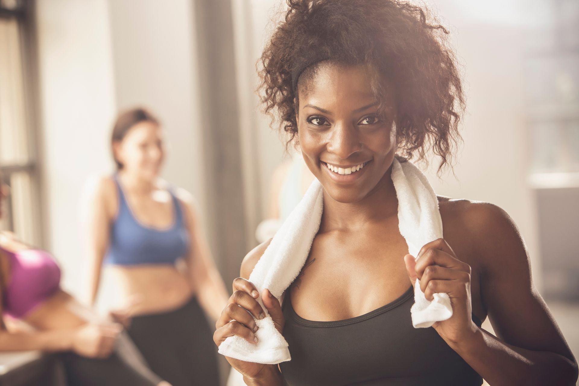 Woman happy in gym setting, highlighting fitness journey with hormone therapy benefits.
