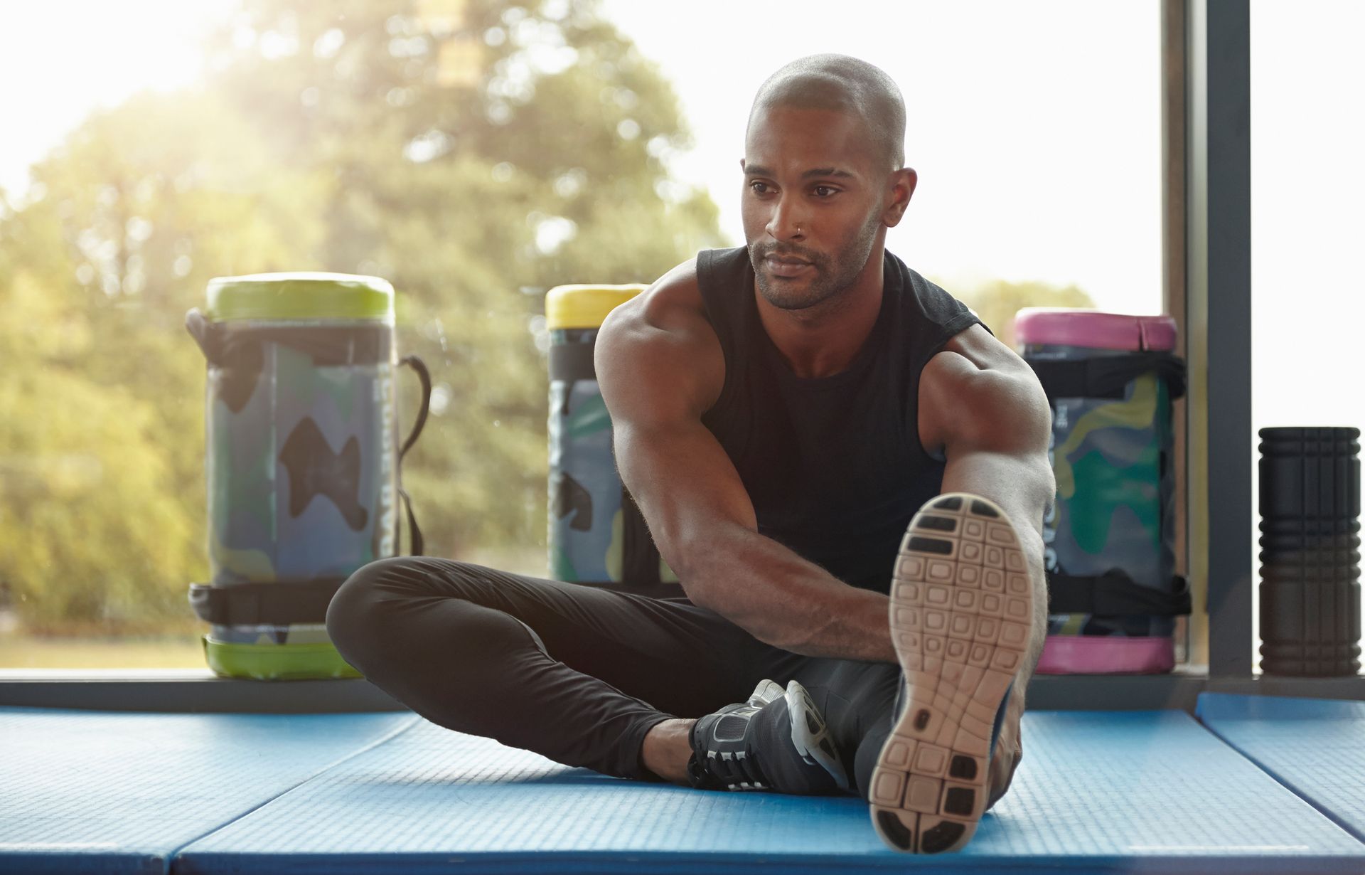 Man stretching hamstrings in gym, showcasing proper form and promoting hormone therapy benefits.