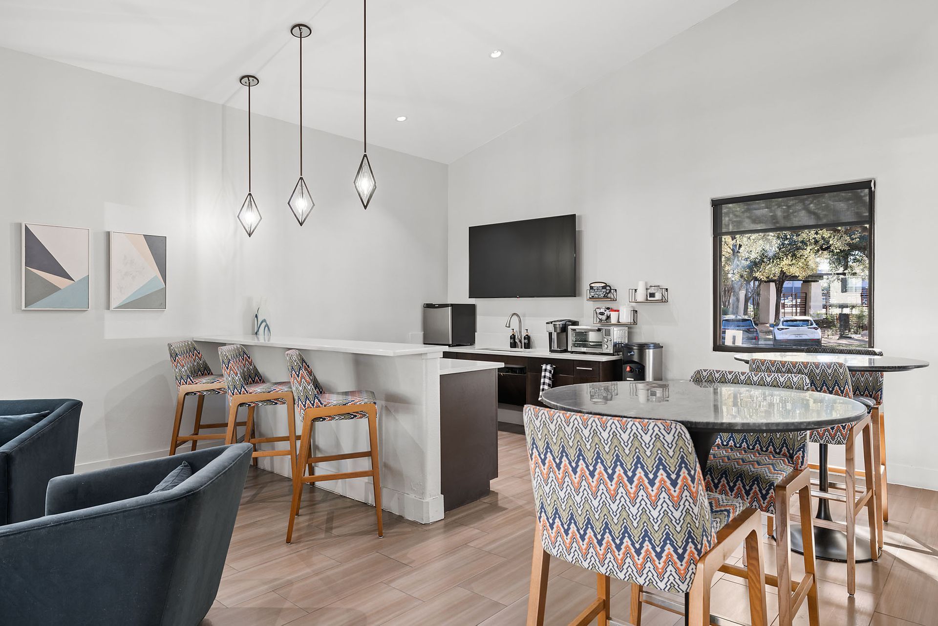 Modern open-concept dining and kitchen area with patterned chairs, island, pendant lights, and wall art at Marquis at Great Hills in Austin, TX.
