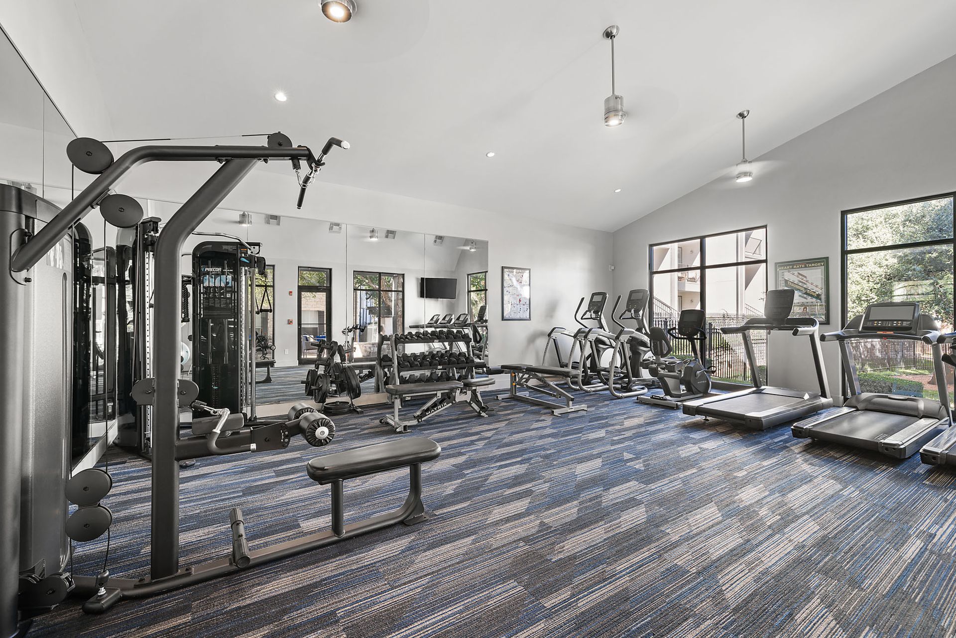 Spacious gym with weight machines, treadmills, and large windows letting in natural light at Marquis at Great Hills in Austin, TX.