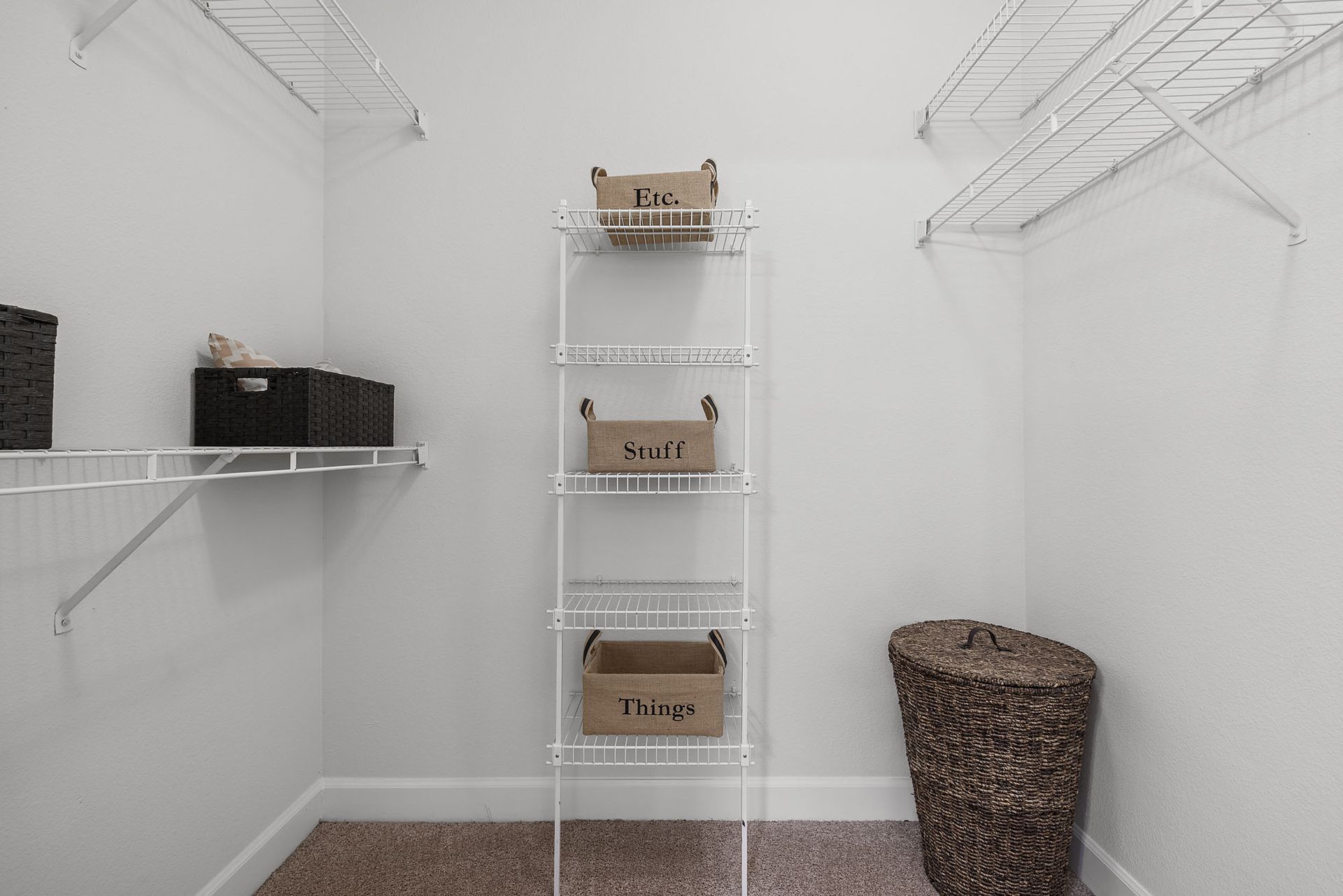 White storage room with wire shelves, wicker basket, and stacked cardboard boxes at Marquis at Great Hills in Austin, TX.
