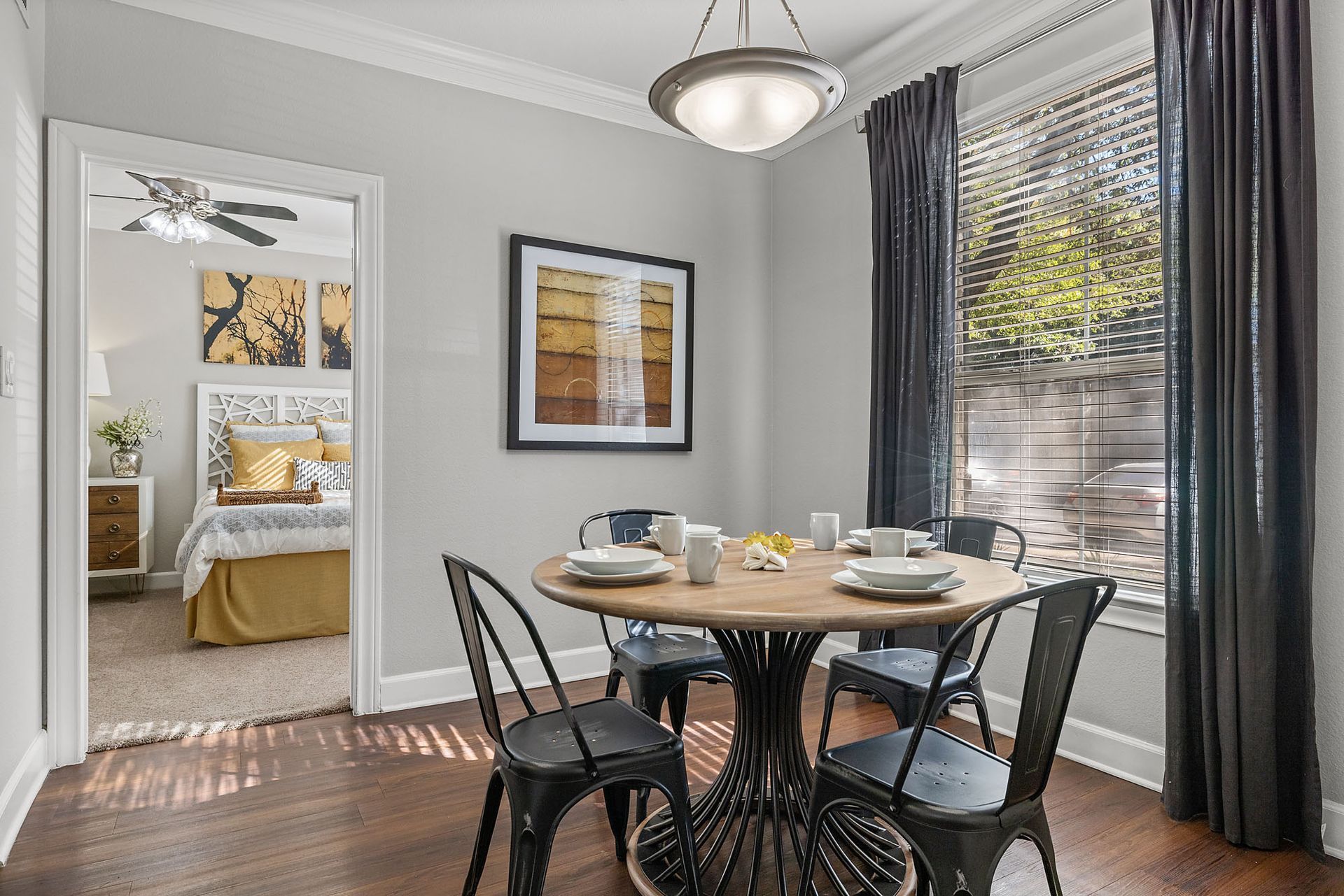Dining nook with round table and black chairs beside large windows, adjacent to a bedroom at Marquis at Great Hills in Austin, TX.