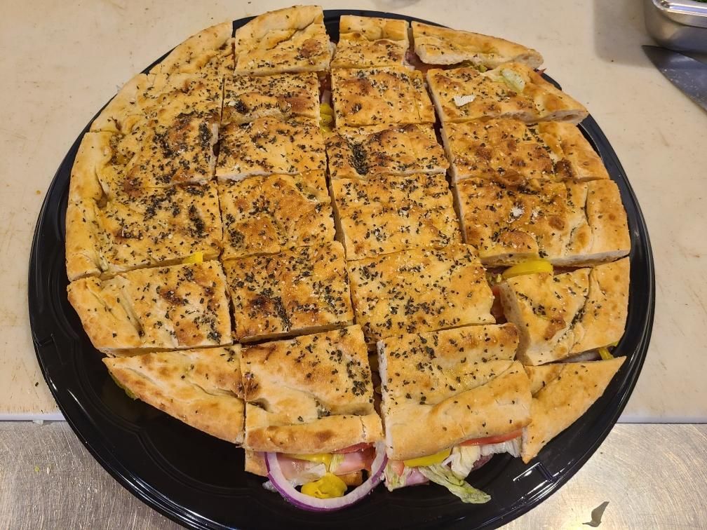 A pizza with a lot of toppings on it is on a black plate.