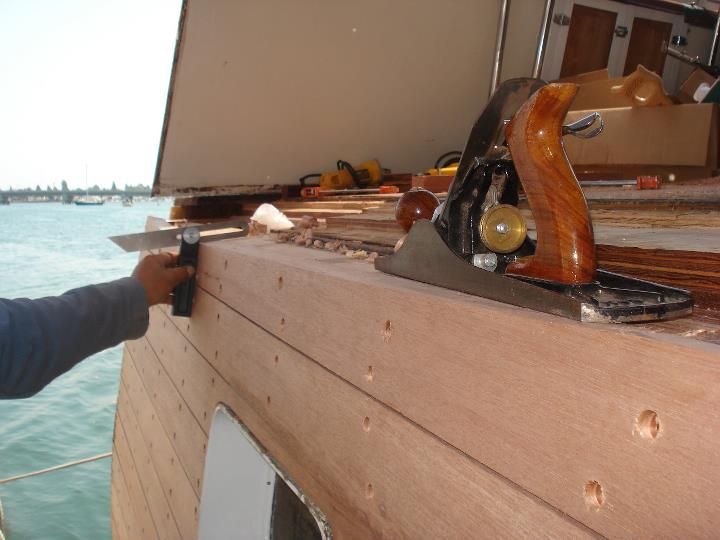 A person is using a plane on a piece of wood