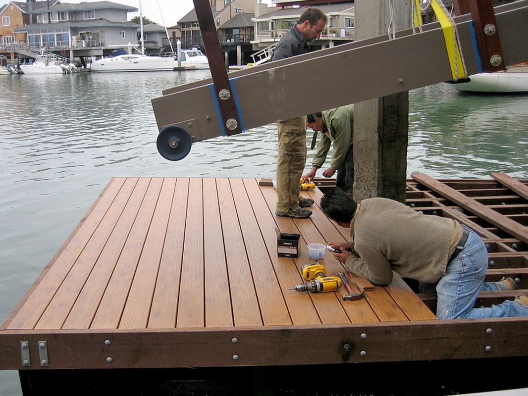 A group of men are working on a wooden dock in the water