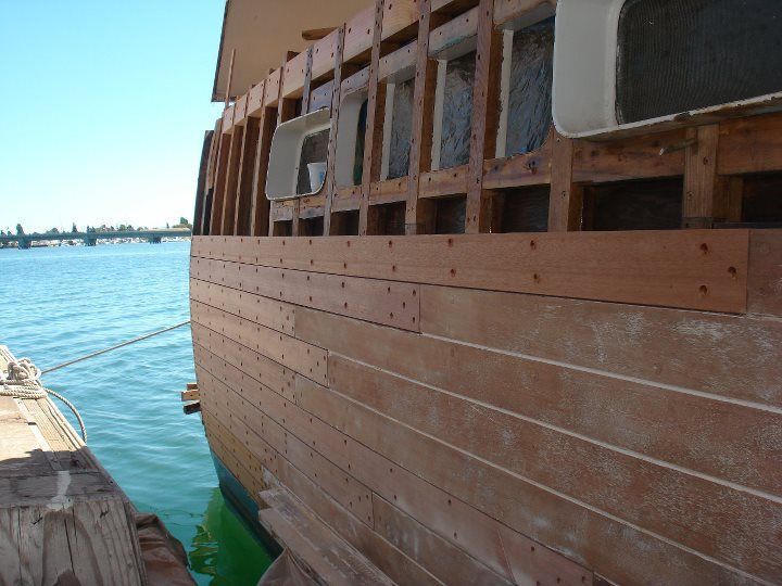 A wooden boat is sitting in the water with a bridge in the background