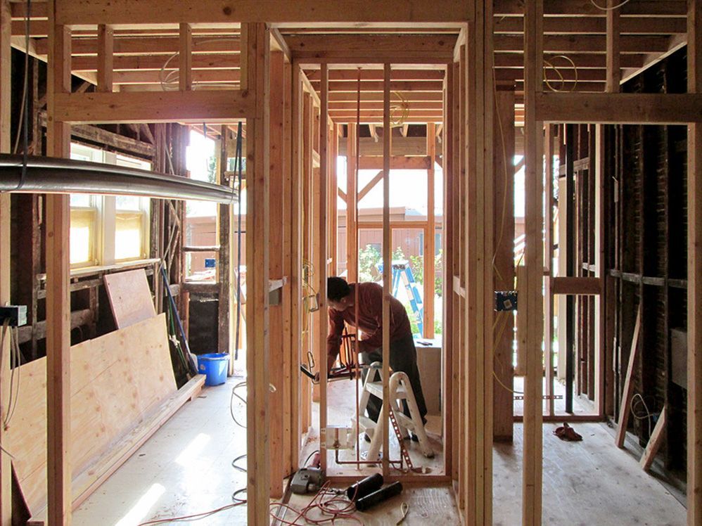 A man is working on a wooden frame of a house.