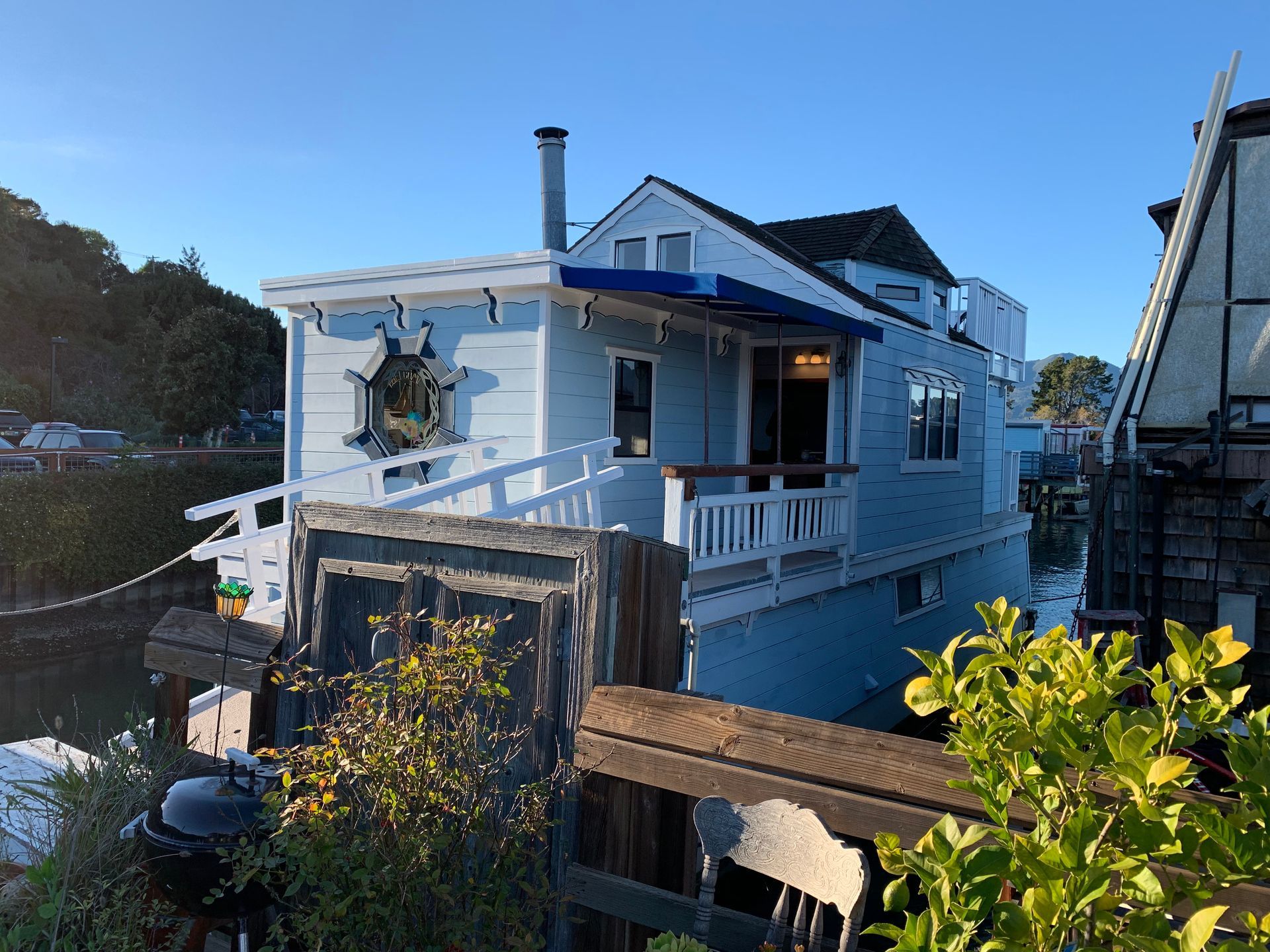 Blue seaside cottage with white trim and porch, viewed from a wooden walkway at dusk