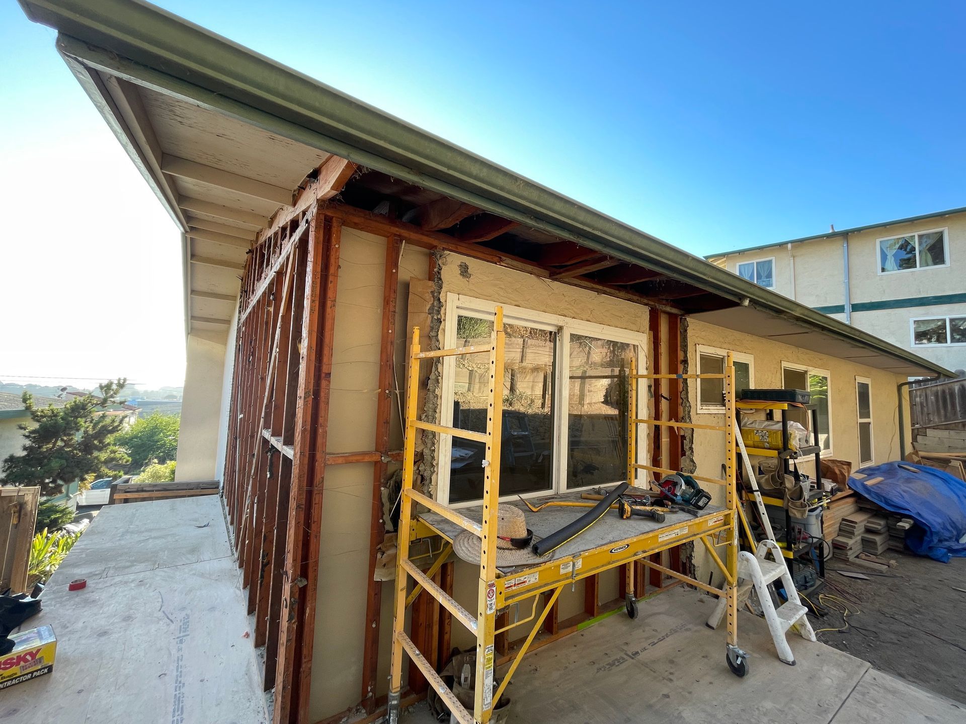 House exterior under renovation with scaffolding, ladder, and construction materials